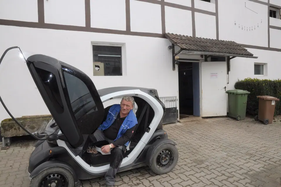 Kleines Elektrofahrzeug vor dem Fachwerkhaus an der Ladestation